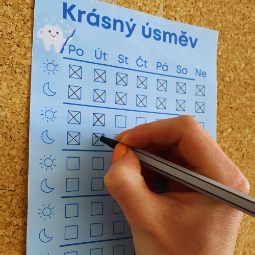 kalendář s názvem krásný úsměv, ruka s propiskou, která píše do kalendáře 