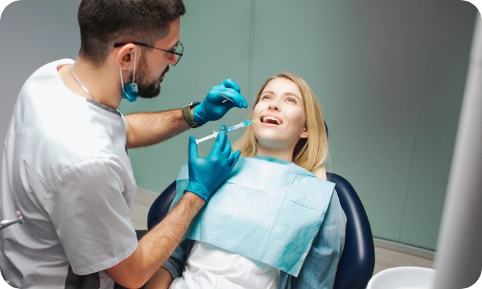 Žena na křesle u dentální hygieny dostává léčbu s injekční stříkačkou naplněnou gengigel kyselinou hyaluronovou.