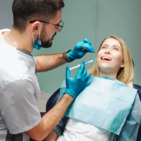 Zubař aplikuje gengigel syringe na dásně pacientky.